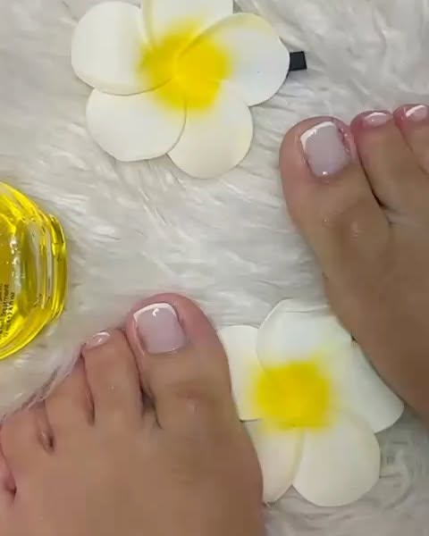 Verzorgde tenen met gellak, tussen witte bloemen, werk van Pedicure Praktijk Maryam